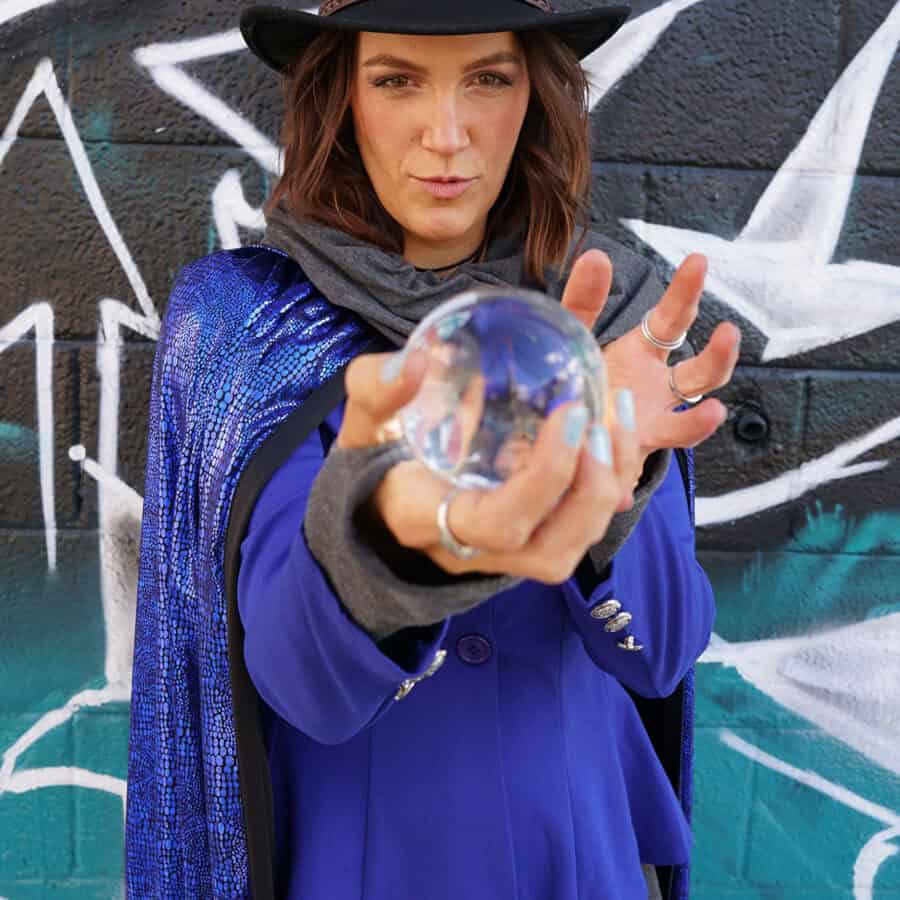 Woman dressed as a wizard holding a crystal ball in hand